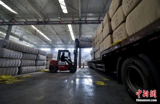新疆喀什綜合保稅區(qū)，喀什啟路國際貿(mào)易有限公司的倉庫內(nèi)，工人正在裝載從塔吉克斯坦和烏茲別克斯坦進(jìn)口的棉花。劉新攝