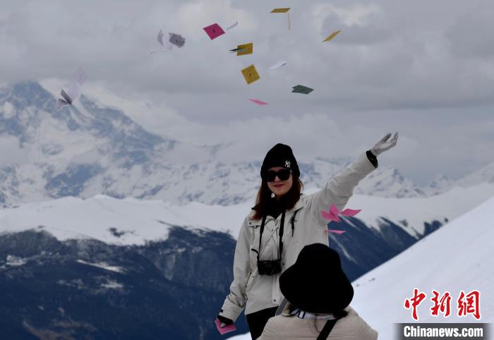圖為5月14日，游客在西藏林芝色季拉山觀景臺(tái)拋灑“隆達(dá)”(風(fēng)馬旗，藏族民眾的一種祈福方式)?！±盍?攝