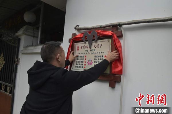 桂溪鎮(zhèn)渭溝村政府工作人員為“十星級文明戶”掛上牌匾?！钣?攝