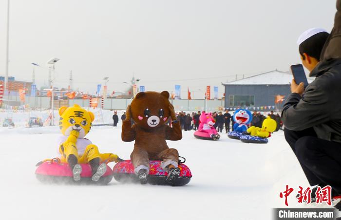 圖為臨夏市南龍鎮(zhèn)馬家莊村舉辦的鄉(xiāng)村文化旅游節(jié)上，游客穿著卡通服裝在體驗雪上飛碟項目。近年來，臨夏州形成了“春賞花、夏避暑、秋摘果、冬玩雪”的全季節(jié)旅游產品體系。(資料圖) 高展 攝